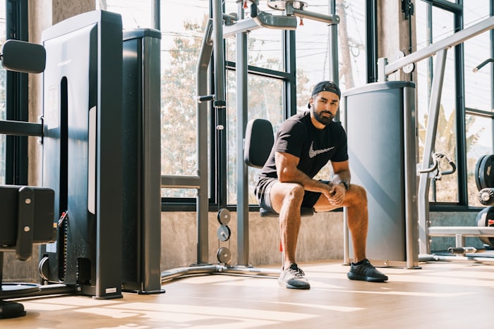 A man resting on a bench between sets at a bright gym