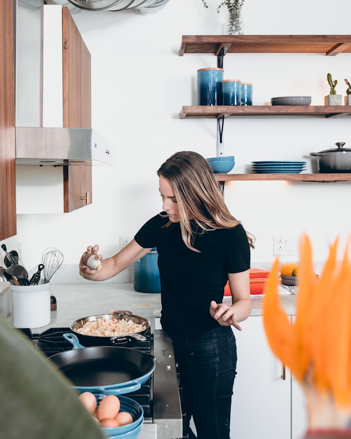 A woman cooking eggs at the stove in a bright kitchen